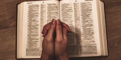 person holding book on brown wooden table